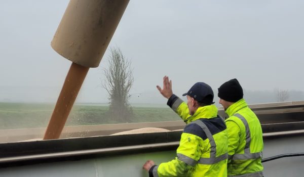 Deux hommes en gilets jaunes à côté d’un grand tuyau.