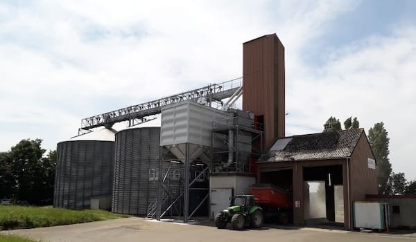 Silo à grains et tracteur stationné à proximité.